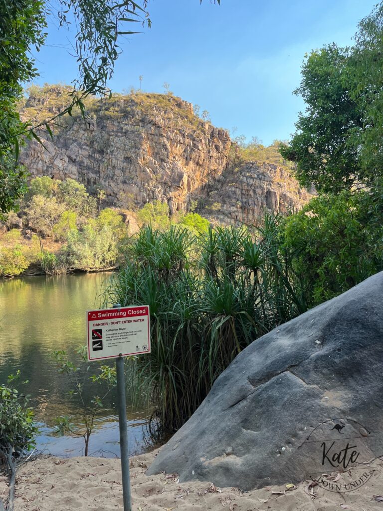 A sign on the bank of the Katherine River that reads Swimming Closed due to crocodiles and dangerous currents