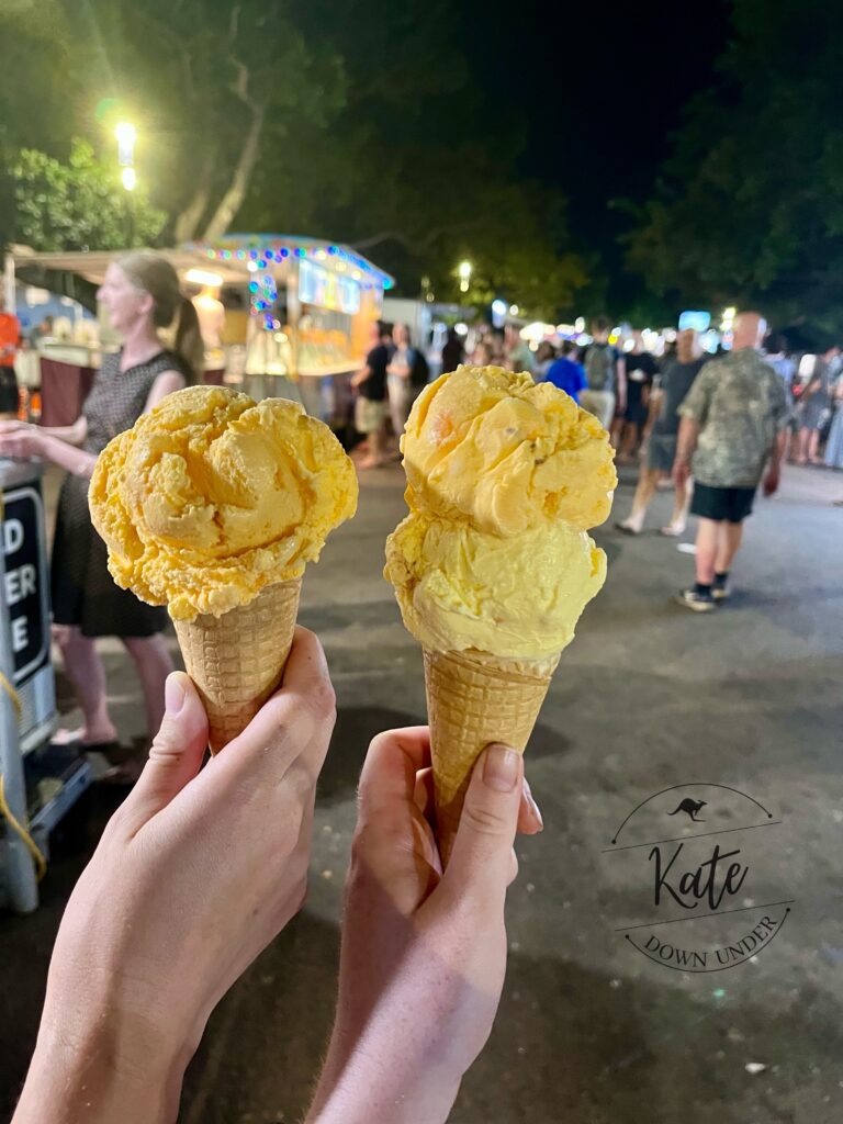 Two ice cream cones, one with one scoop of orange ice cream, and one with a scoop of orange and a scoop of yellow ice cream