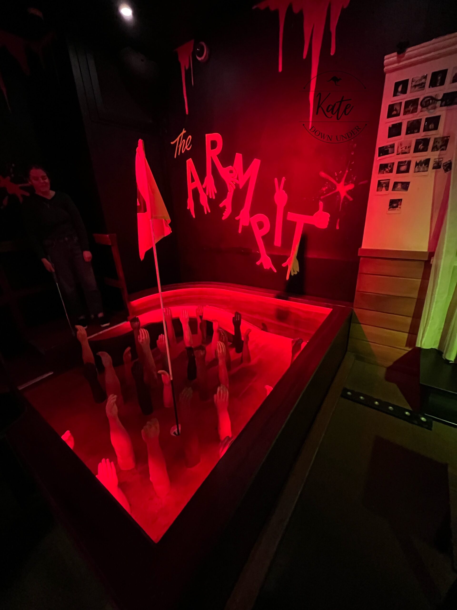 A mini golf hole consisting of an elevated teeing platform and a pit filled with mannequin forearms