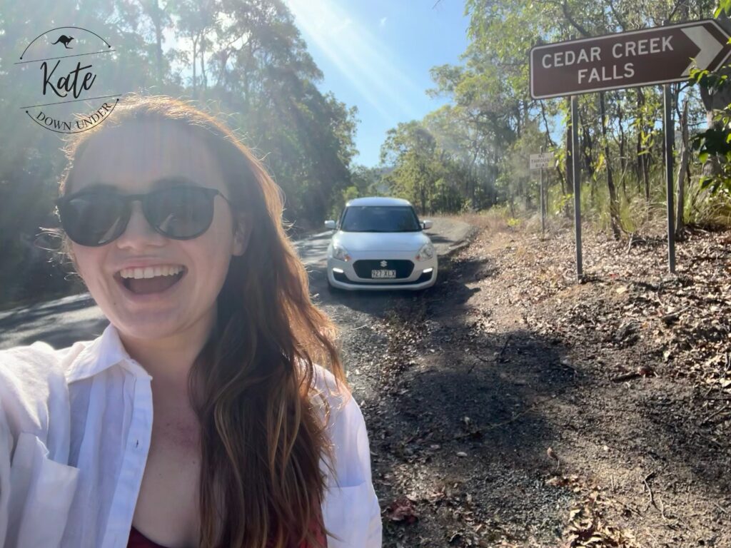 Kate taking a selfie with the cedar creek falls sign and her rental car