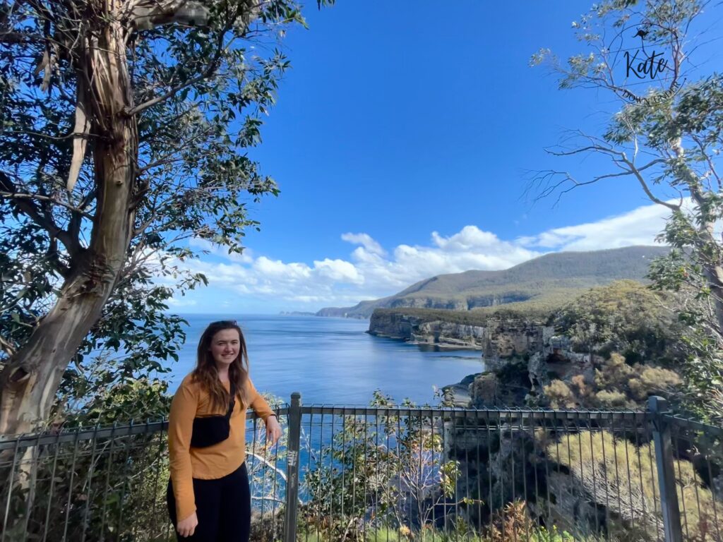 Kate standing on the lookout platform, with cliffs dropping into the Tasman Sea in the background