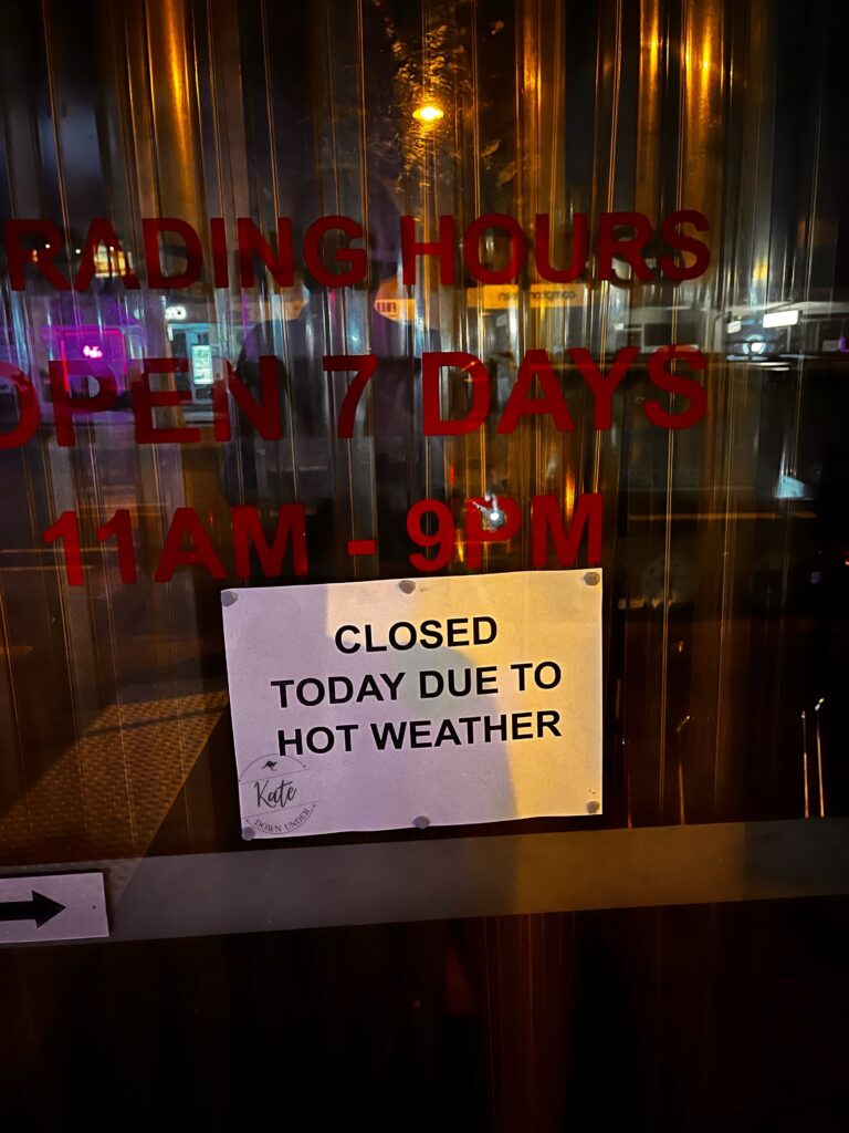 a sign in a shop window that reads 'closed today due to hot weather'